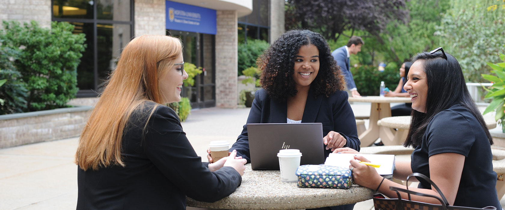 Three Students Meeting Together at a Table Outside on Campus