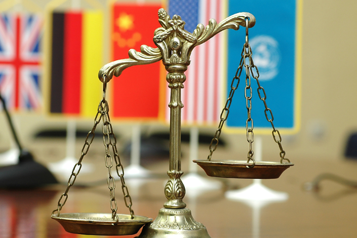 A balance scale with various flags in the background representing international law.