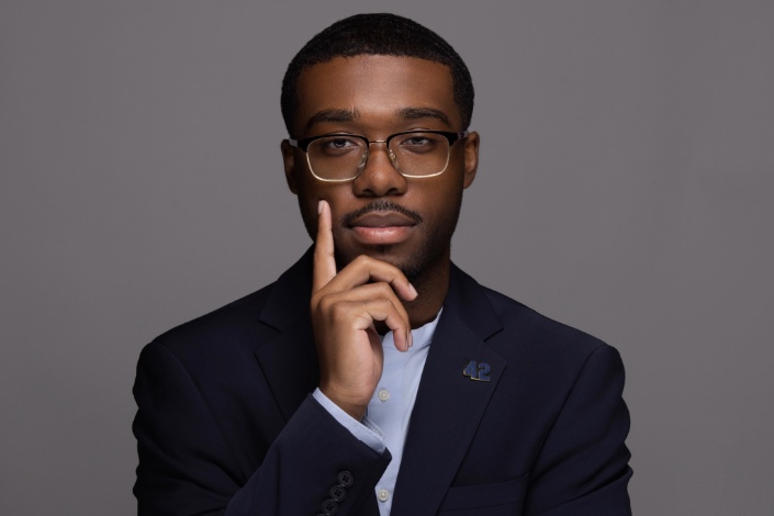 A headshot of third-year Hofstra Law student Oneil Gibson with a gray background behind him.